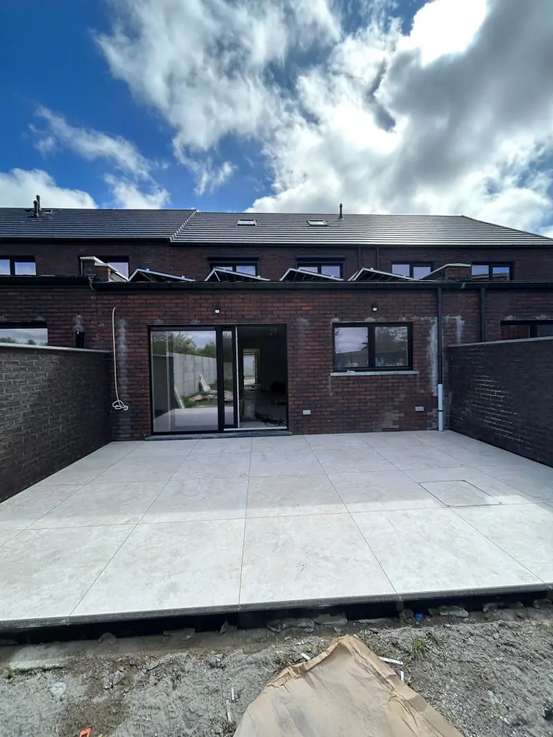 Terrasse en carrelage grand format posée par KMPOSE à l'arrière d'une maison
